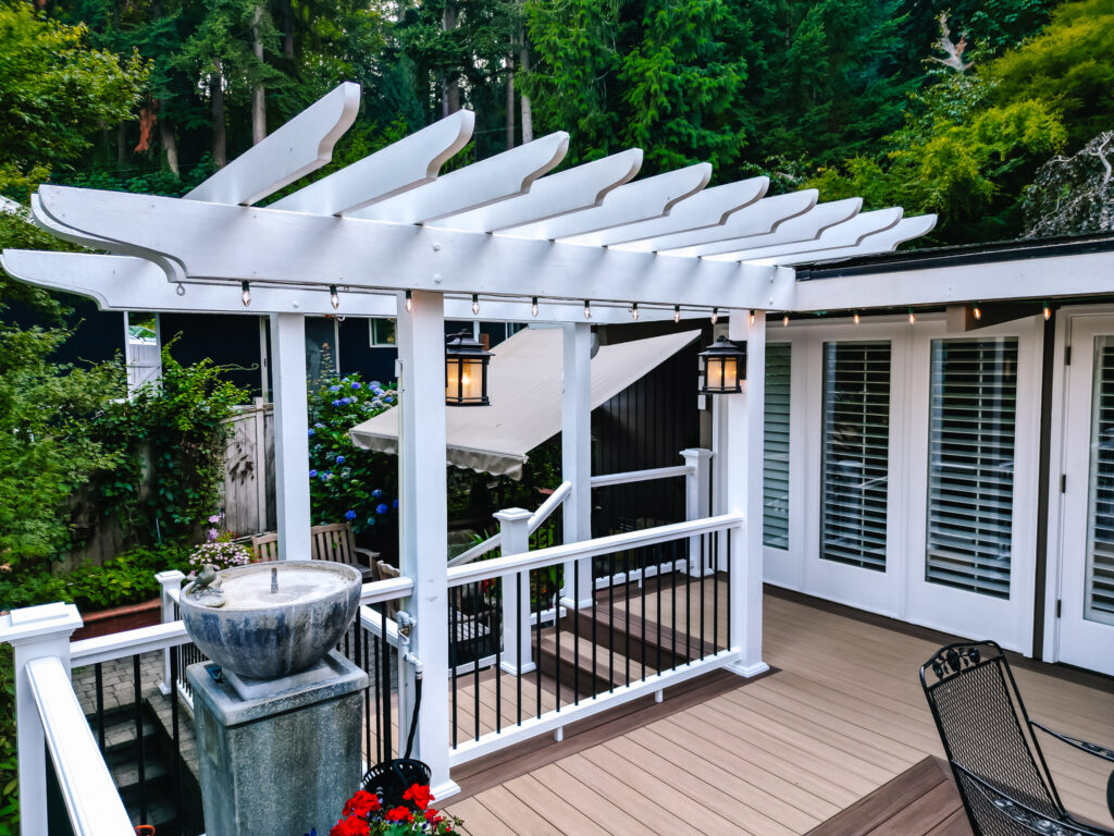 Vertical surface mount black post white rail composite railing with two tone Azek Decking and pergola