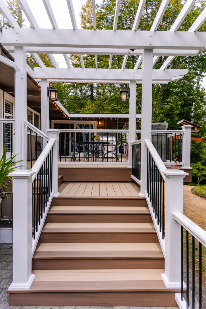 Vertical surface mount black post white rail composite railing with two tone Azek Decking and pergola