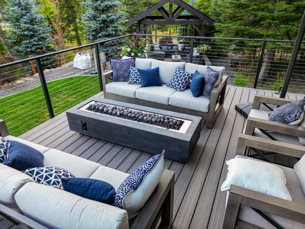 Wrap around deck with modern furniture and a rectangular fire pit.